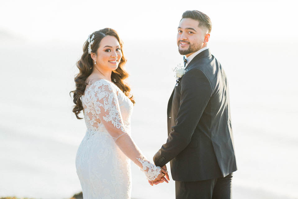 Mussel Rock Wedding Photo, A gorgeous couple in their wedding attire in on a cliff at mussel rock in daly city overlooking the pacific ocean 